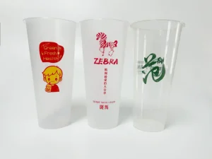 Disposable plastic cups with colorful branding prints, including a zebra design and bubble tea graphics, printed with the AP-600-8 Automatic Cup Printing Machine. Demonstrates multi-color printing precision for disposable beverage packaging.
